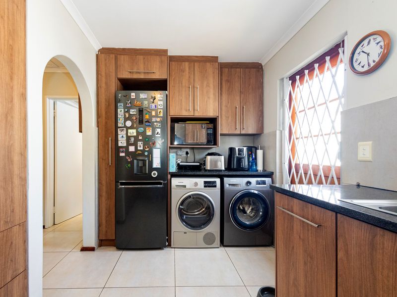 Functional laundry area featuring wood-finish cabinetry, granite countertops, and tiled flooring, providing efficient space for appliances and utility tasks.