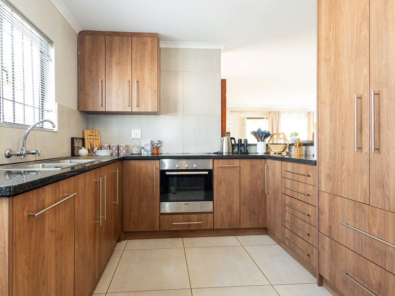 A well-maintained kitchen featuring wood-finish cabinetry, granite countertops, a built-in oven, and tiled flooring, offering a functional and modern workspace.