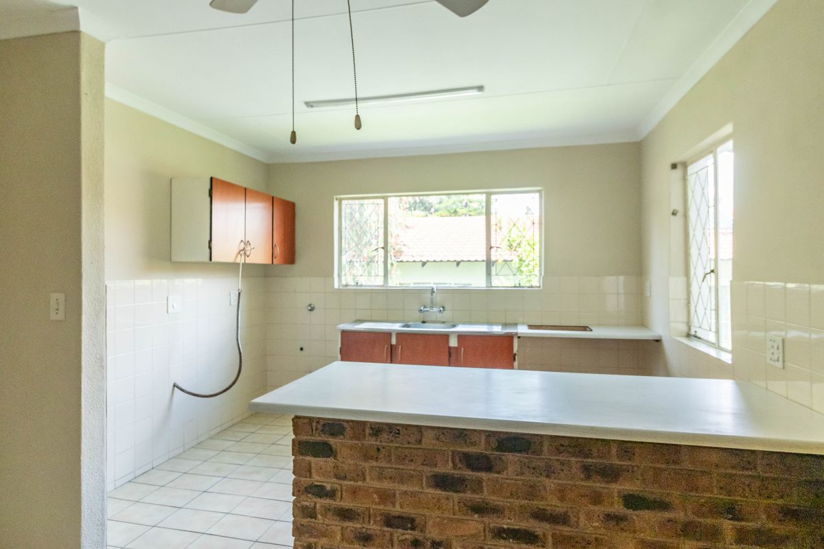 A functional, empty kitchen featuring a brick breakfast bar, tiled splashbacks, and built-in cabinetry, offering a blank canvas for modern renovation.