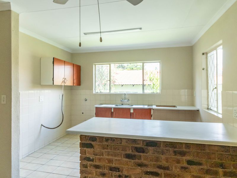 A functional, empty kitchen featuring a brick breakfast bar, tiled splashbacks, and built-in cabinetry, offering a blank canvas for modern renovation.