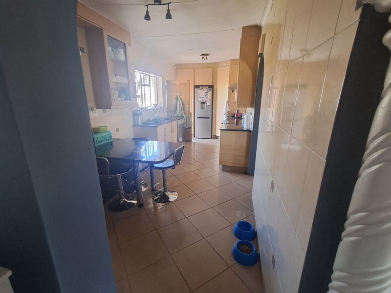 A functional kitchen featuring tiled flooring, extensive built-in cabinetry, and a tiled splashback, offering a practical layout for daily meal preparation.