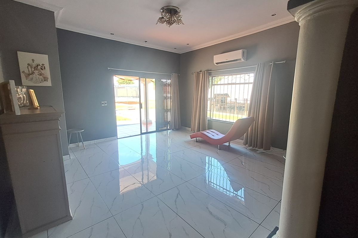 Spacious living room featuring polished porcelain tile flooring, a split-system air conditioner, and direct access to the outdoor patio area through sliding glass doors.