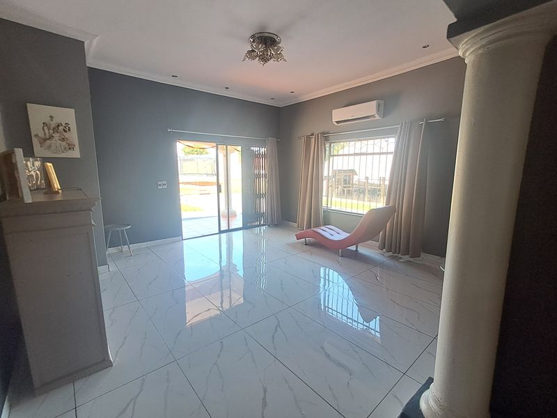 Spacious living room featuring polished porcelain tile flooring, a split-system air conditioner, and direct access to the outdoor patio area through sliding glass doors.