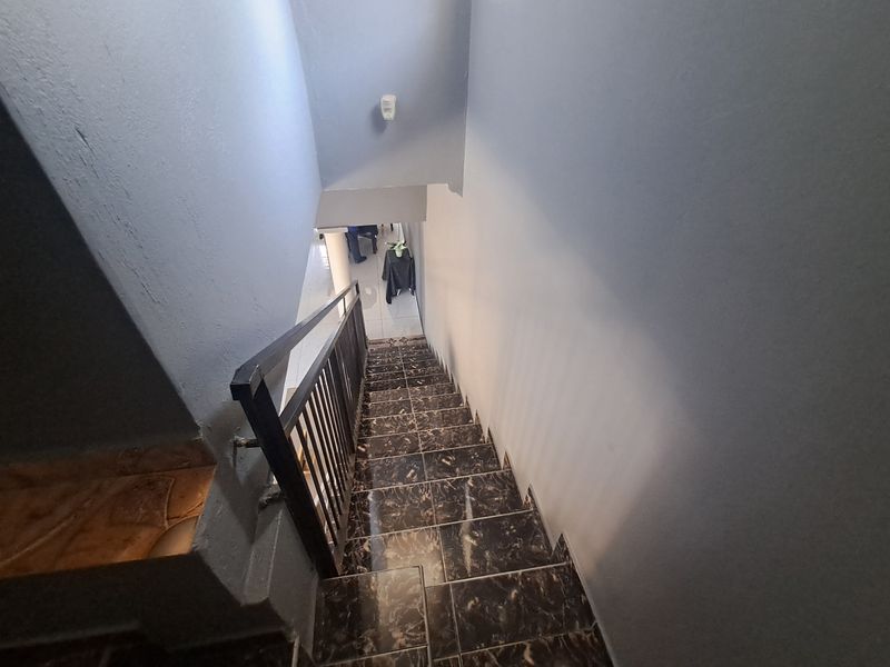 A functional staircase featuring dark marble-effect tiled steps and a simple metal balustrade, providing access between levels.