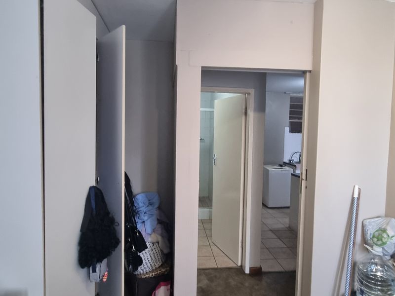A functional hallway featuring built-in cupboards, providing access to adjacent rooms including a tiled bathroom and kitchen area.