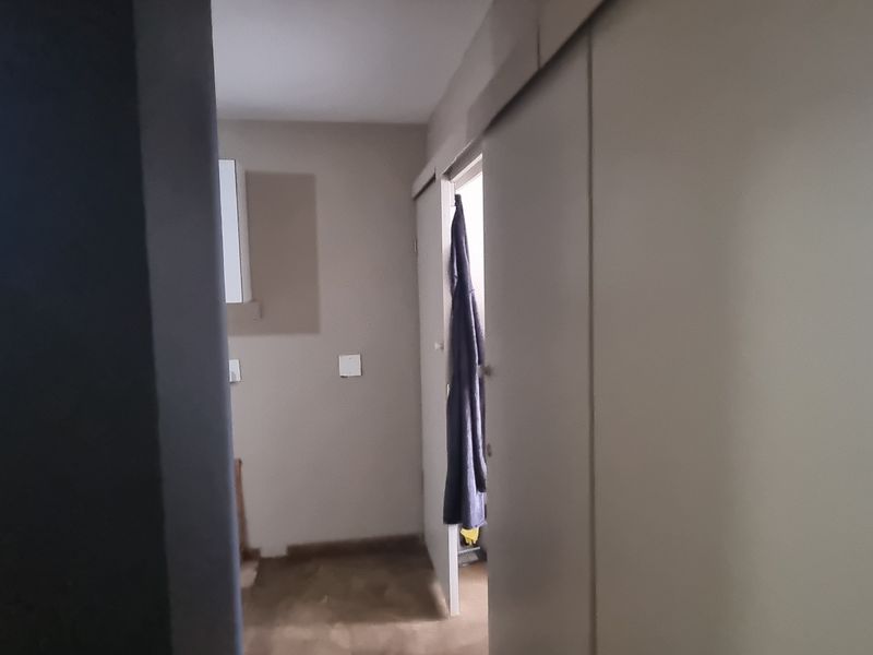 A functional hallway area featuring built-in cupboard storage and a sliding door, providing access to adjacent rooms within the flat.