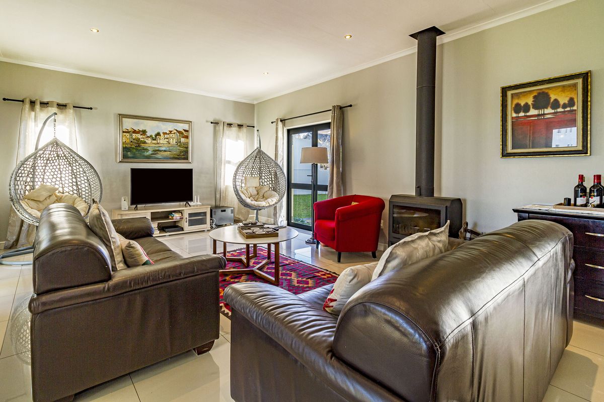 Spacious living room featuring tiled flooring, a modern freestanding fireplace, and direct access to the garden through a glass sliding door.
