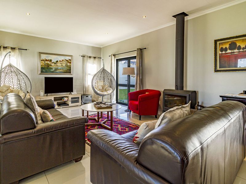 Spacious living room featuring tiled flooring, a modern freestanding fireplace, and direct access to the garden through a glass sliding door.