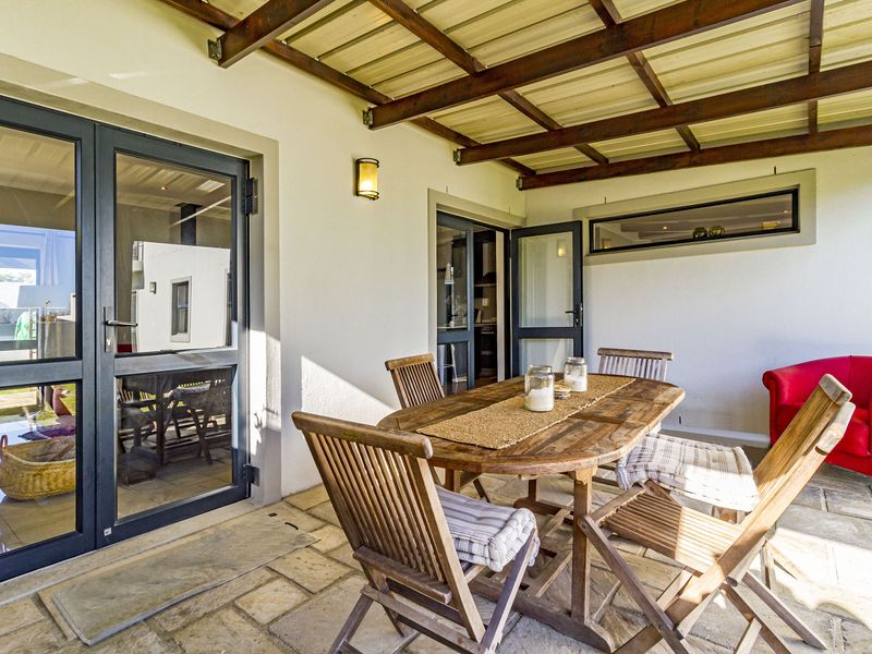 A covered patio area featuring stone paving, a timber pergola structure, and direct access to the interior through aluminium framed glass doors.