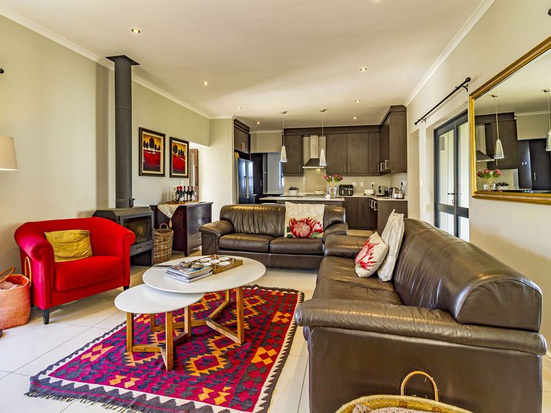 Spacious open-plan living area featuring a modern kitchen, tiled floors, recessed lighting, and a cozy freestanding fireplace, seamlessly connecting to the outdoor space.
