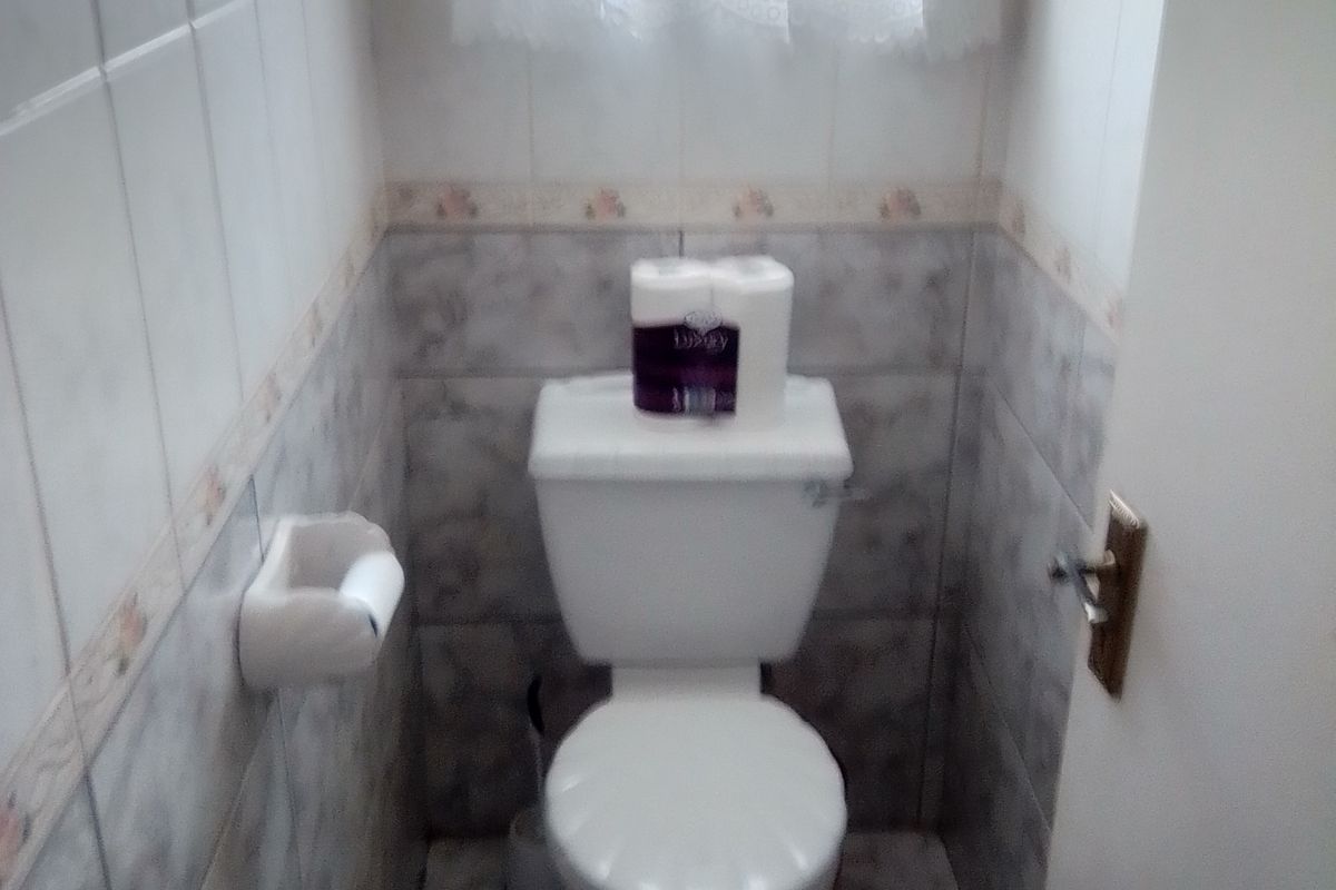 A compact guest toilet featuring neutral ceramic wall and floor tiles.