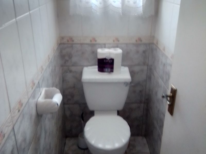 A compact guest toilet featuring neutral ceramic wall and floor tiles.