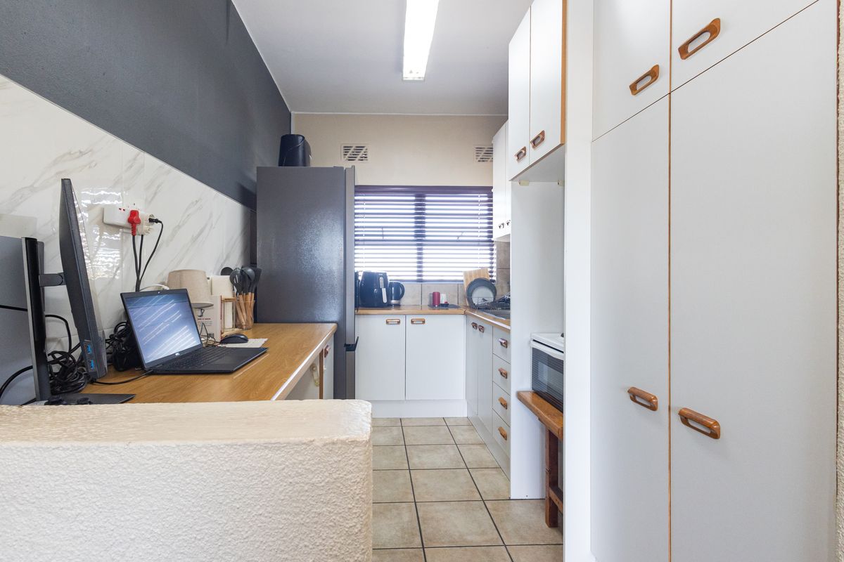 A functional kitchen featuring white cabinetry, laminate countertops, tiled flooring, and a built-in oven, offering a practical layout for daily meal preparation.