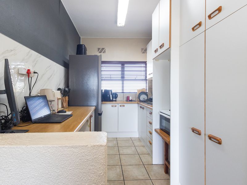 A functional kitchen featuring white cabinetry, laminate countertops, tiled flooring, and a built-in oven, offering a practical layout for daily meal preparation.