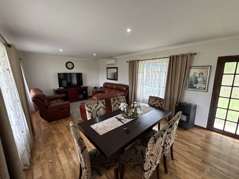 Spacious open-plan living and dining area featuring laminate flooring, recessed lighting, and a split-system air conditioner with direct access to the exterior.