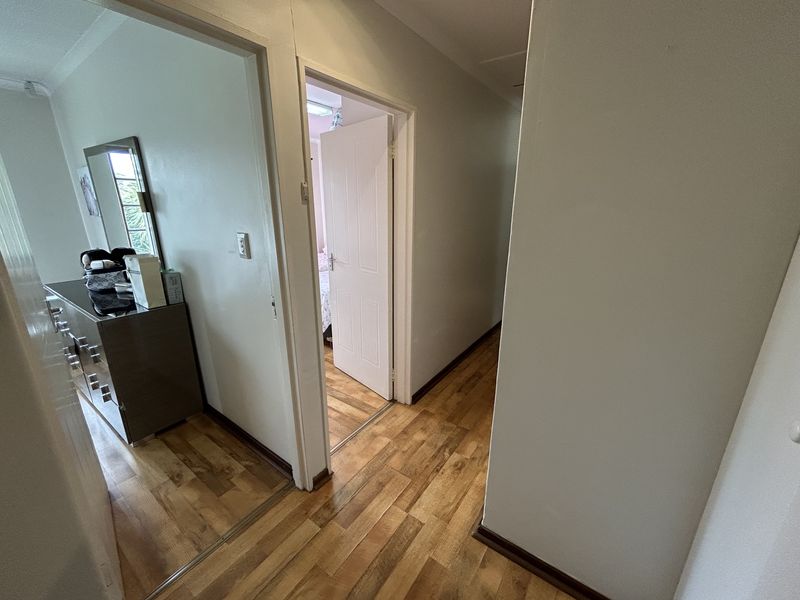 A functional hallway featuring laminate wood flooring and access to adjacent rooms through standard internal doors.