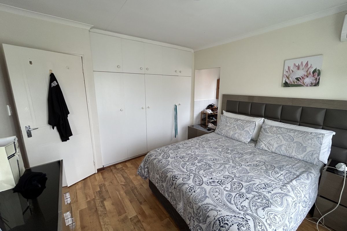 A well-maintained bedroom featuring laminate flooring, built-in cupboards, and an integrated air conditioning unit.