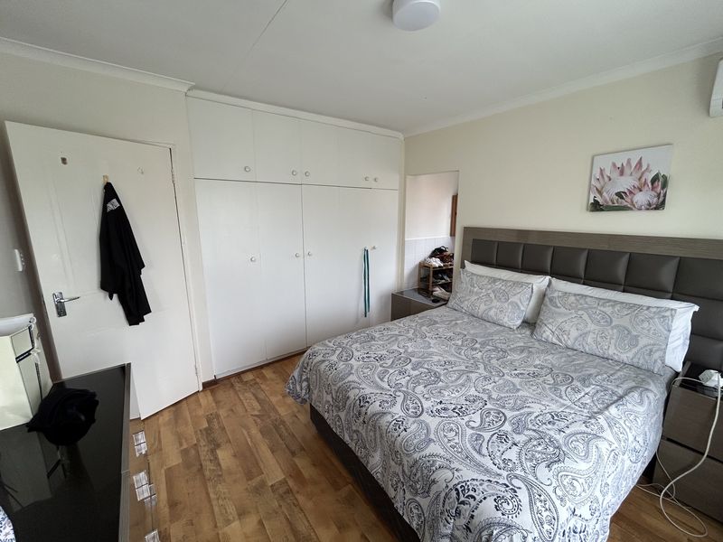 A well-maintained bedroom featuring laminate flooring, built-in cupboards, and an integrated air conditioning unit.