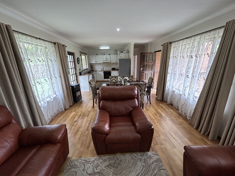 Spacious open-plan living and dining area featuring hardwood flooring, coved cornicing, and a functional kitchen with built-in cabinetry and appliances.