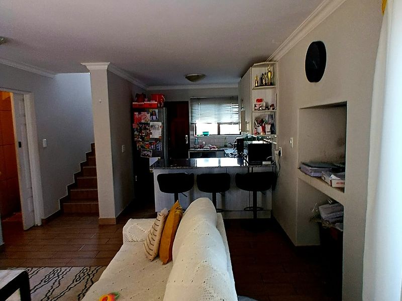 Open plan living area featuring a kitchen with island, tiled flooring, and a staircase leading to the upper level.