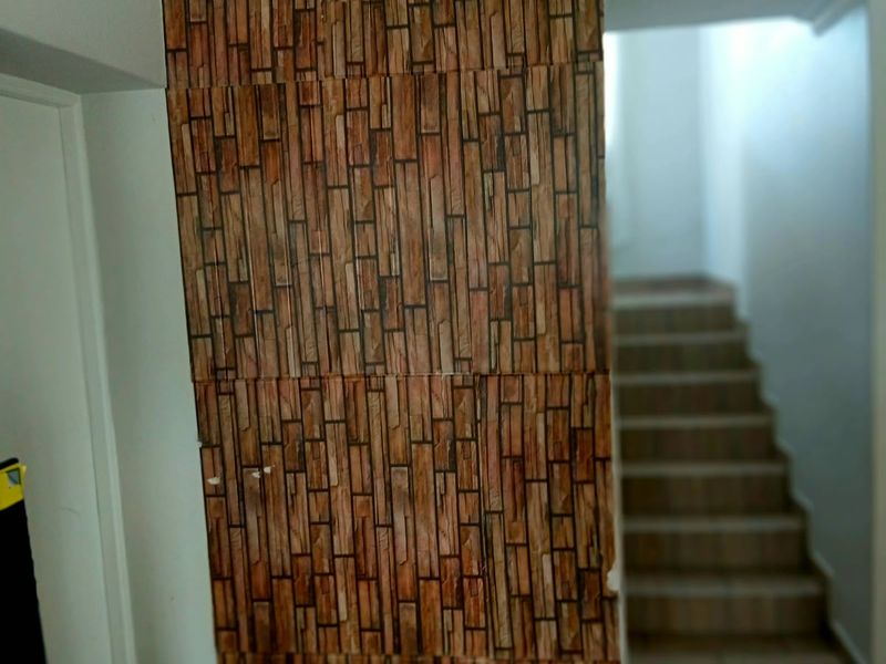 A hallway featuring a staircase and a decorative feature wall with brick-effect wallpaper, leading to an upper level.