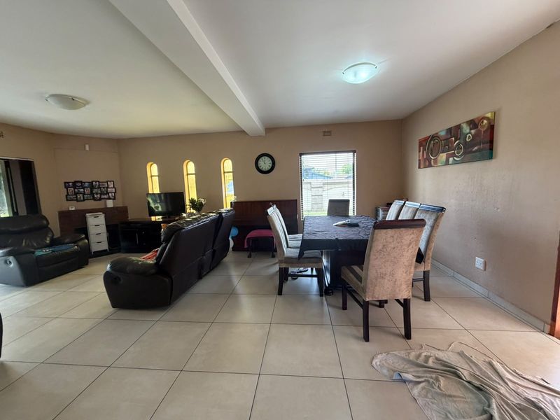 Spacious open-plan living and dining area featuring neutral tiled flooring, arched windows, and a functional layout suitable for family living.
