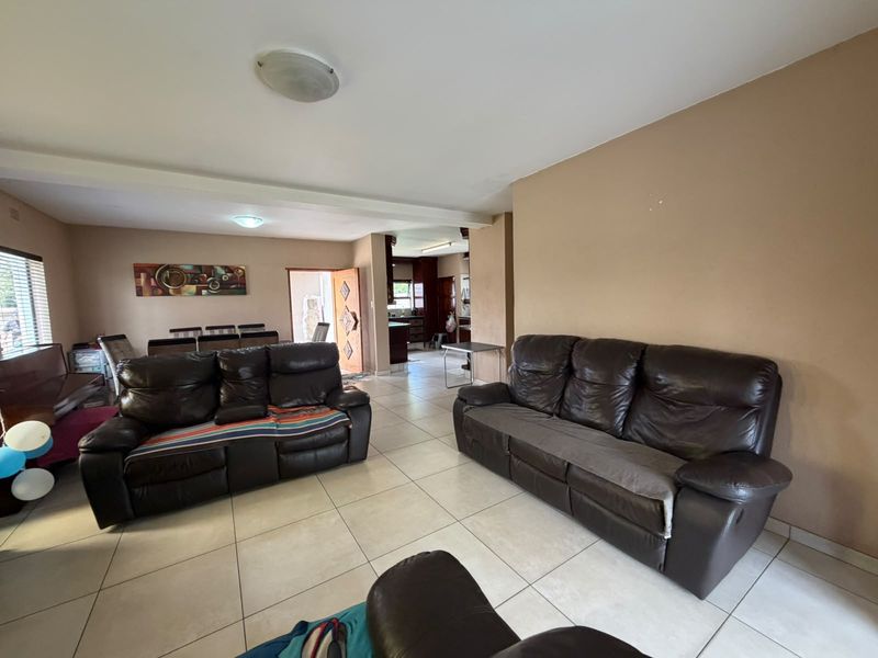 Spacious open-plan living and dining area featuring neutral tiled flooring and direct access to the kitchen area.