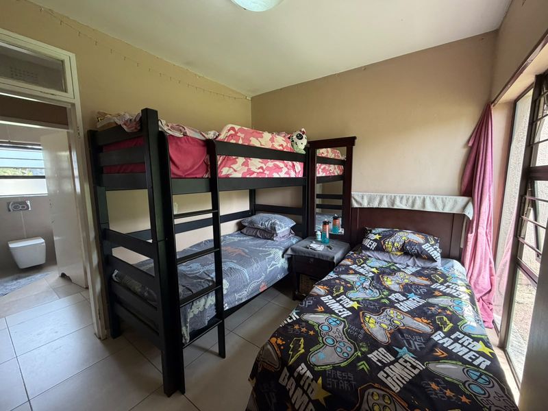 A bedroom featuring tiled flooring and a sliding glass door with access to an adjacent bathroom.