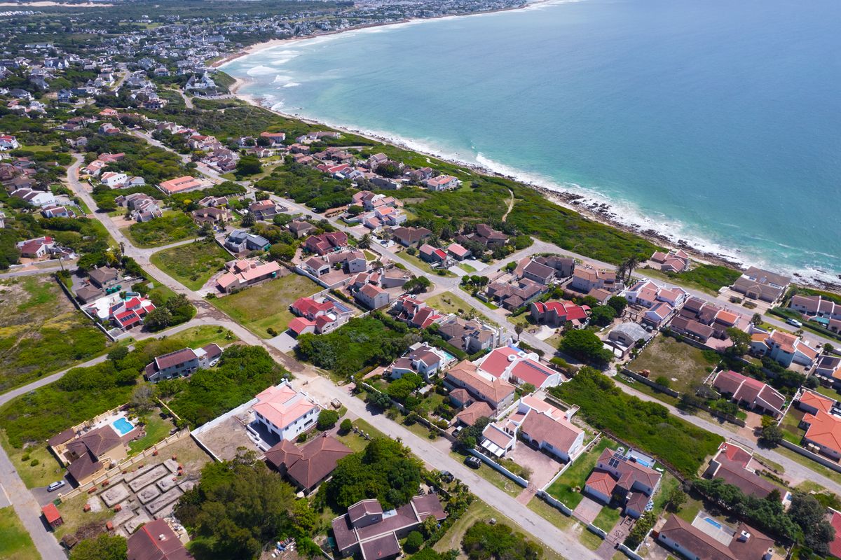 An aerial view of a coastal residential neighborhood, showcasing the proximity to the ocean and the surrounding suburban layout.