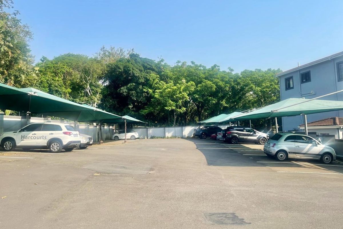 Outdoor parking area featuring multiple shade cloth carports and asphalt paving, situated within a residential apartment complex.