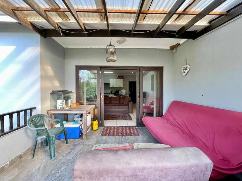 Covered patio area featuring tiled flooring, timber roof structure, and sliding glass doors providing access to the interior living space.