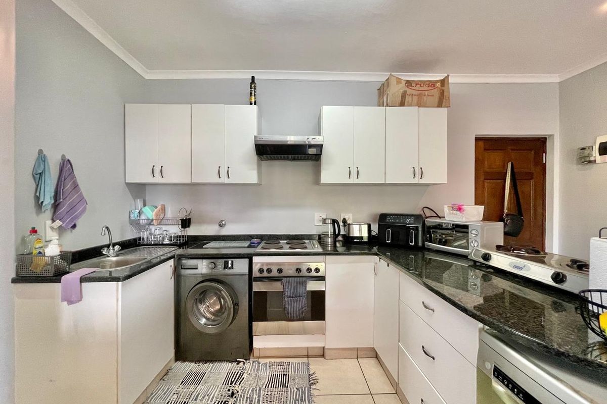 Functional kitchen featuring granite countertops, built-in cabinetry, integrated oven and hob, and tiled flooring, providing a practical workspace for daily cooking.