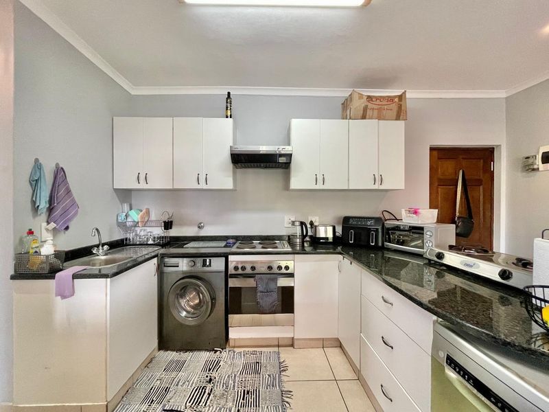 Functional kitchen featuring granite countertops, built-in cabinetry, integrated oven and hob, and tiled flooring, providing a practical workspace for daily cooking.