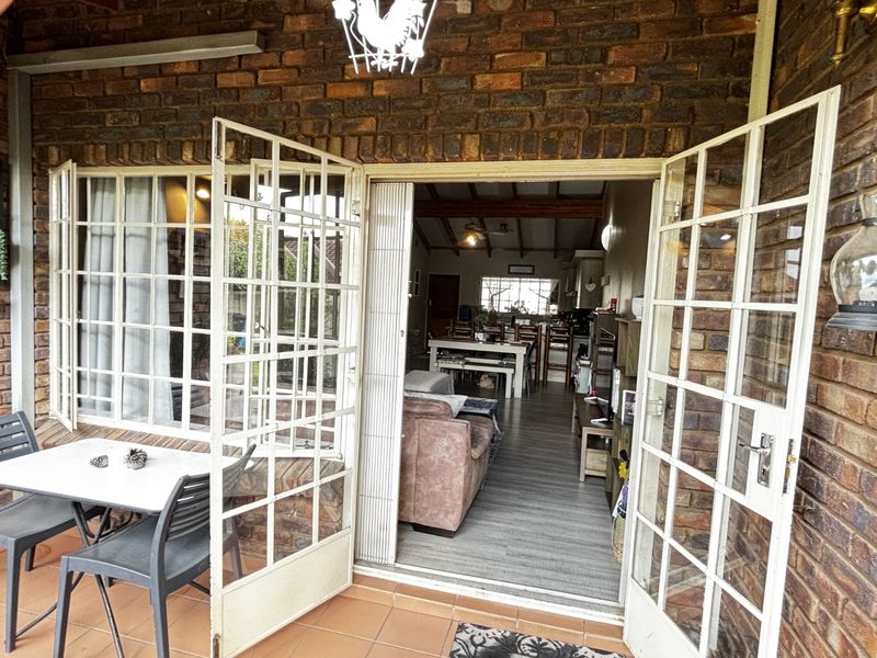 Covered patio area featuring exposed brick walls and tiled flooring, providing seamless access to the interior living space through double french doors.