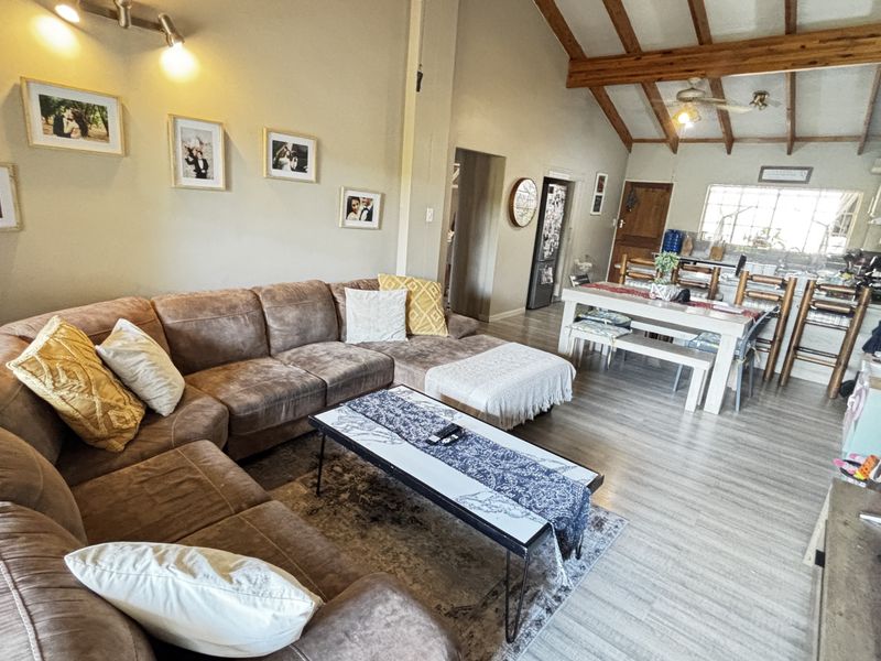 Spacious open-plan living and dining area featuring exposed timber ceiling beams, laminate flooring, and a functional kitchen with an island.