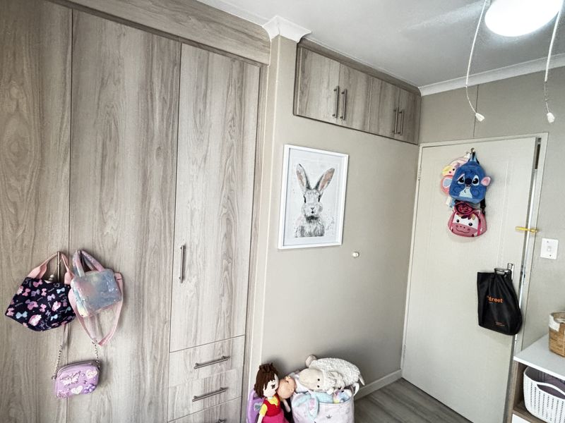 A bedroom featuring light wood-grain built-in cupboards and overhead storage cabinets, providing ample integrated storage space.