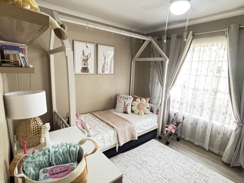 A cozy bedroom featuring laminate flooring, neutral wall tones, and built-in shelving, offering a comfortable and well-maintained living space.