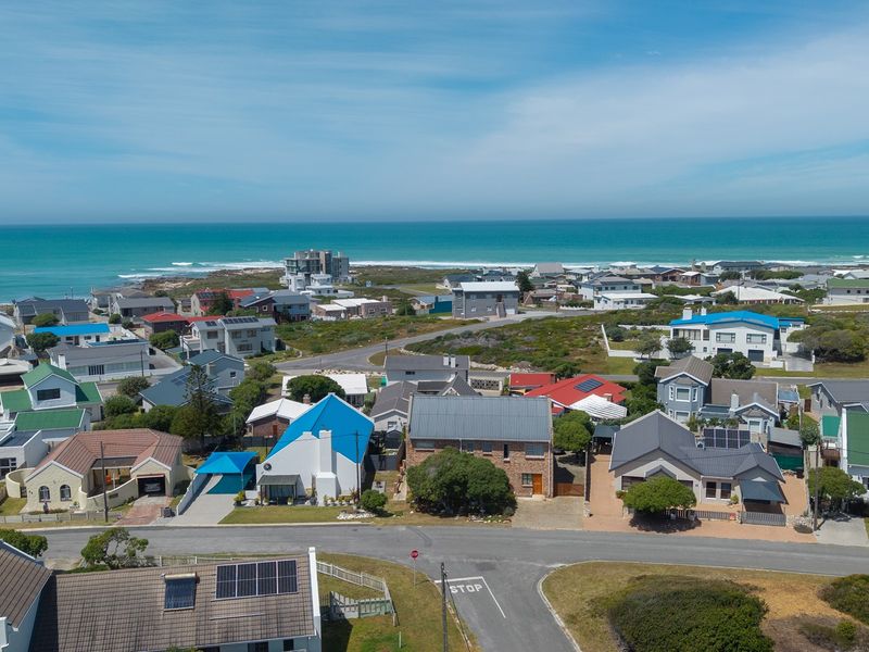 An aerial view of a coastal residential neighborhood featuring various homes with diverse roof styles and proximity to the ocean.