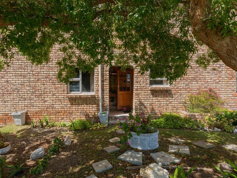 Front elevation of a face brick house featuring a timber entrance door, aluminium window frames, and a landscaped garden area.
