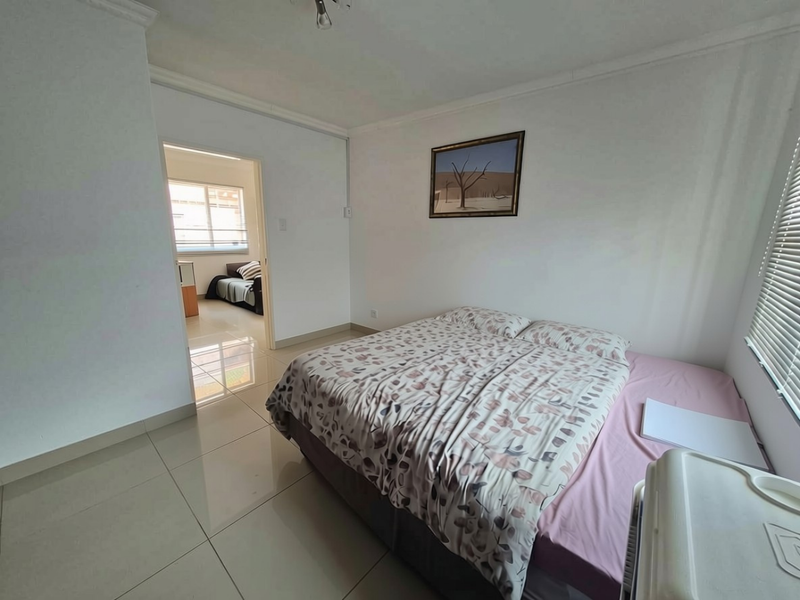 A bedroom featuring tiled flooring, coving, and venetian blinds, with an open doorway leading to an adjacent room.