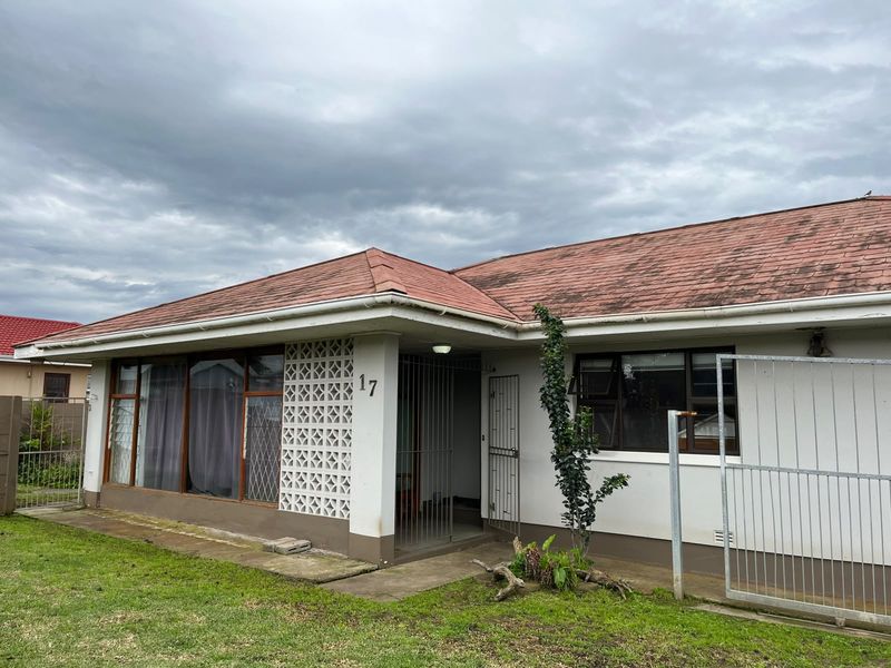 Front elevation of a single-story house featuring a distinctive breeze block screen, tiled roof, and security gate entrance.