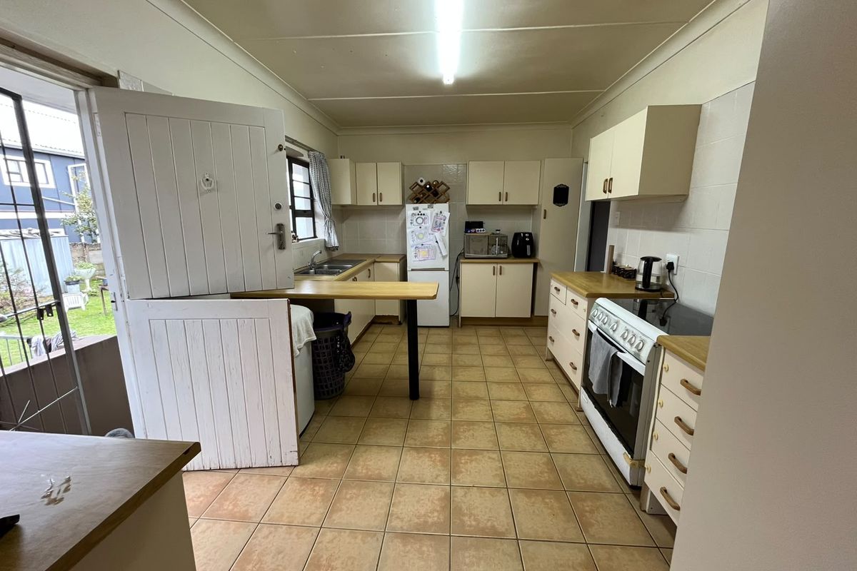 A functional kitchen featuring tiled flooring, built-in cabinetry, a double sink, and a classic stable door providing direct access to the exterior.
