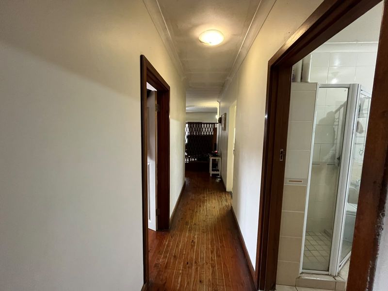 A functional hallway featuring polished timber flooring, coved ceilings, and access to adjacent rooms including a bathroom.