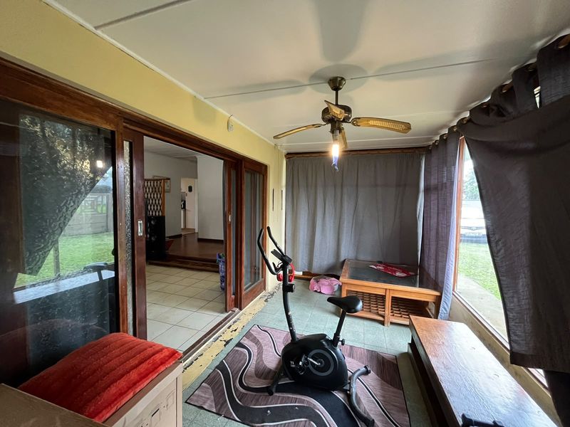 Enclosed patio area featuring tiled flooring, a ceiling fan, and large sliding glass doors providing access to the interior living space.