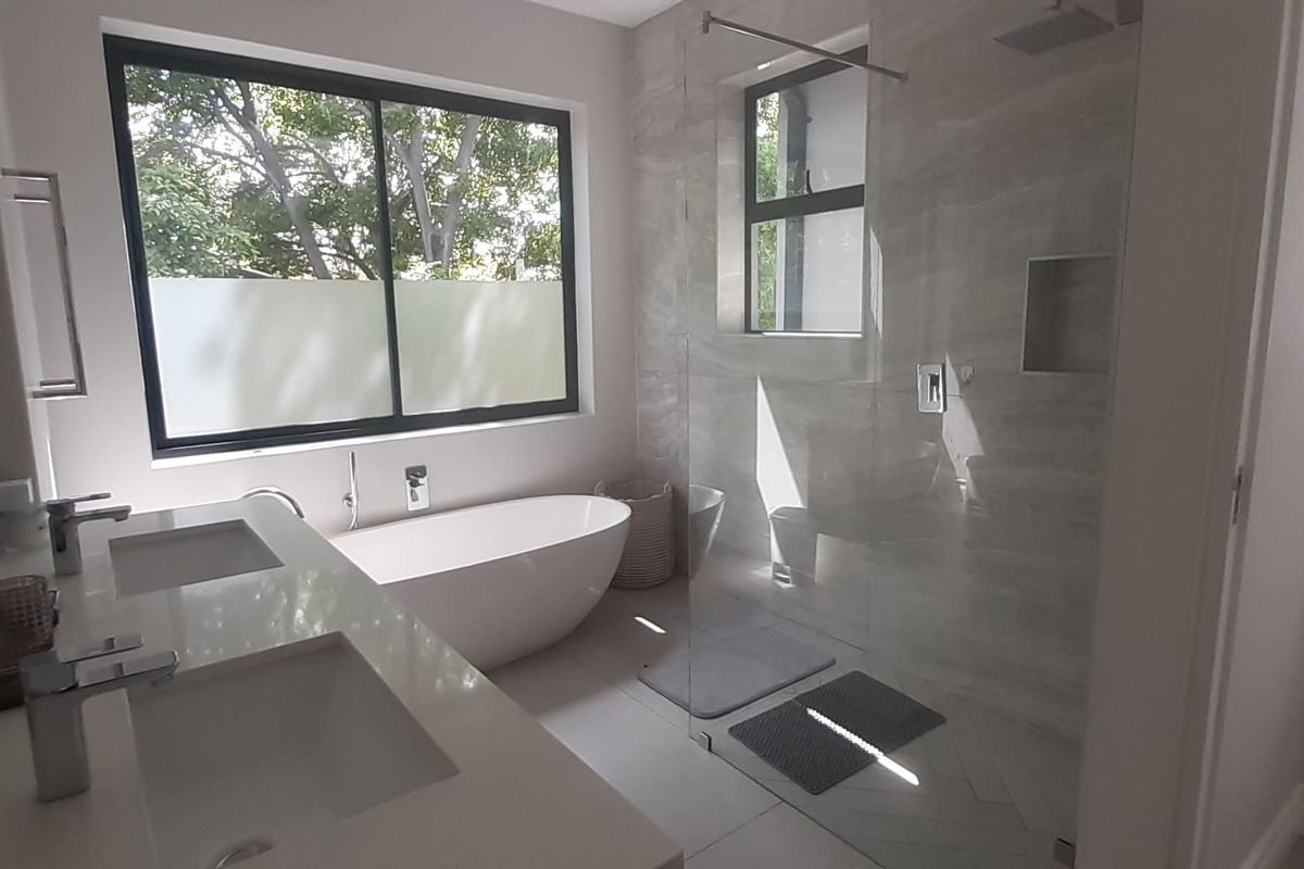 Modern bathroom featuring a double vanity, a sleek freestanding bathtub, and a spacious walk-in shower with a recessed niche and contemporary finishes.