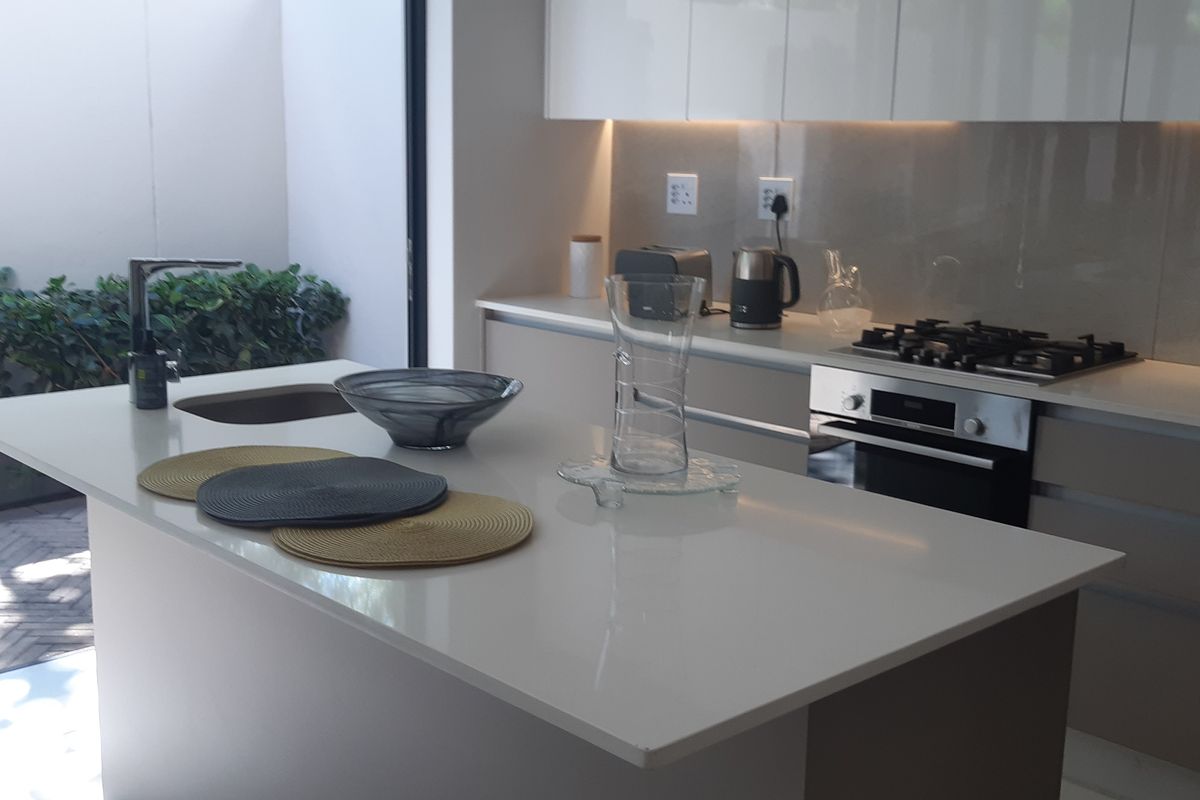Modern kitchen featuring a central island with stone countertops, built-in oven, gas hob, and sleek cabinetry, with direct access to an outdoor patio area.