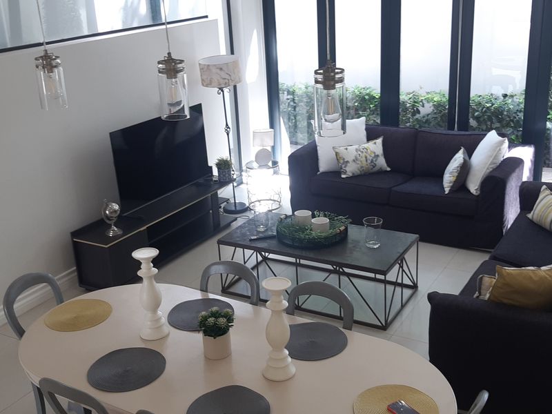 Spacious open-plan living and dining area featuring high ceilings, tiled floors, and large glass sliding doors that provide abundant natural light.