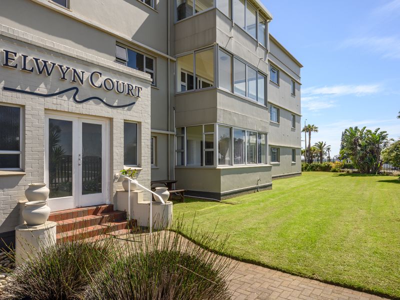 Exterior view of Selwyn Court apartment building featuring a well-maintained lawn, paved entrance walkway, and enclosed balcony structures.
