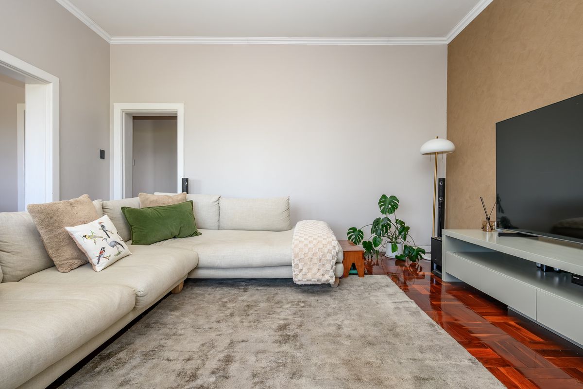 A well-maintained living room featuring rich parquet flooring, crown molding, and a textured accent wall, creating a warm and inviting atmosphere.
