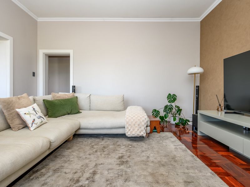 A well-maintained living room featuring rich parquet flooring, crown molding, and a textured accent wall, creating a warm and inviting atmosphere.